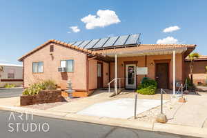 View of front of house featuring a tile roof, stucco siding, and solar panels