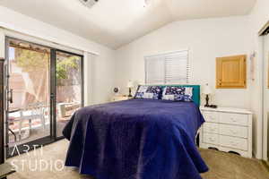 Carpeted bedroom featuring vaulted ceiling and access to outside