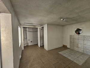 Empty room featuring tile patterned floors, a baseboard heating unit, and a textured ceiling