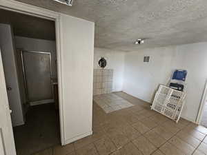 Tiled spare room with baseboards and a textured ceiling
