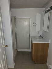 Bathroom with a stall shower, vanity, and a textured wall