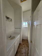 Bathroom featuring vanity, shower / bathtub combination, and dark tile patterned flooring