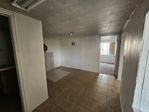Tiled empty room featuring a textured wall and a textured ceiling