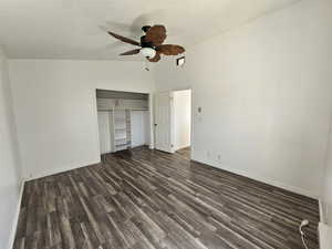 Unfurnished bedroom with a closet, dark wood-type flooring, a ceiling fan, lofted ceiling, and a textured ceiling