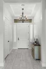 Foyer entrance featuring a raised ceiling and a chandelier
