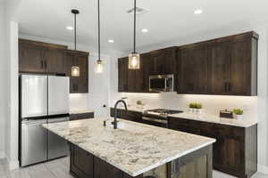 Kitchen with dark brown cabinetry, stainless steel appliances, decorative backsplash, and recessed lighting