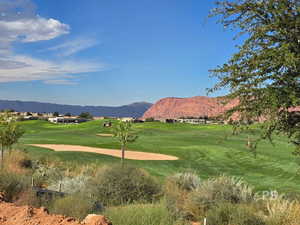 View of community with view of golf course, a mountain view, and a yard