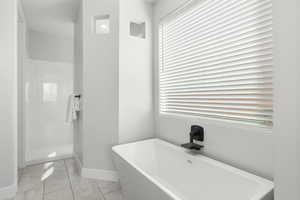 Full bath featuring a freestanding tub, a shower stall, and light tile patterned floors