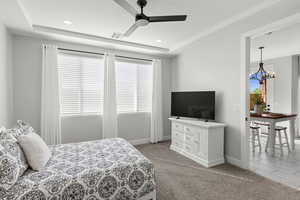 Bedroom with a raised ceiling, light carpet, a chandelier, ceiling fan, and recessed lighting