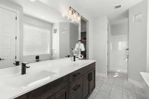 Full bath featuring double vanity, a soaking tub, a shower stall, and a walk in closet