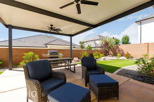 Fenced backyard with a patio, a ceiling fan, a grill, and an outdoor hangout area