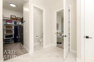 Bathroom featuring light marble finish floors and a walk in closet