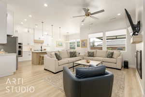 Living area with light wood-style floors, recessed lighting, ceiling fan, and a fireplace