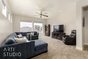 Carpeted living area featuring ceiling fan and recessed lighting