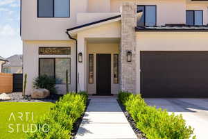 Property entrance with stucco siding, a garage, concrete driveway, and stone siding