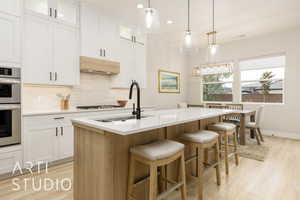 Kitchen with backsplash, white cabinets, pendant lighting, light wood finished floors, and recessed lighting