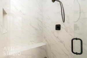 Full bath with a marble finish shower
