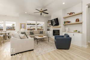 Living area featuring a glass covered fireplace, light wood-style flooring, recessed lighting, a ceiling fan, and built in features
