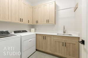 Laundry room featuring washer and dryer, cabinet space, and light tile patterned floors