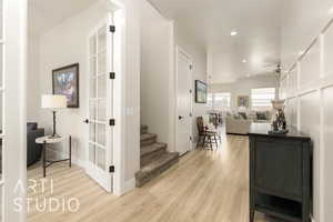 Hallway with light wood-type flooring, recessed lighting, and stairway