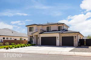 View of front of property with stone siding, concrete driveway, a garage, a standing seam roof, and stucco siding