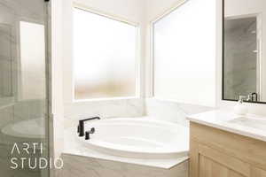Full bath featuring vanity, a garden tub, and a marble finish shower