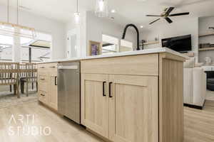 Kitchen with light brown cabinets, light wood-type flooring, open floor plan, stainless steel dishwasher, and a ceiling fan