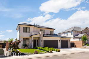 View of front of house with concrete driveway, stone siding, and stucco siding