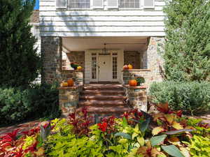 View of exterior entry with stone siding and covered porch
