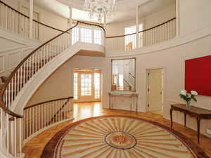 Staircase featuring a high ceiling, a decorative wall, ornamental molding, a chandelier, and a wainscoted wall