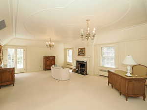 Sitting room featuring a decorative wall, a chandelier, a fireplace with flush hearth, carpet floors, and radiator heating unit