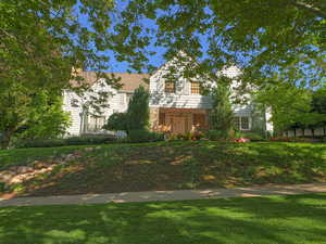 Traditional-style house with a front lawn, stone siding, and covered porch