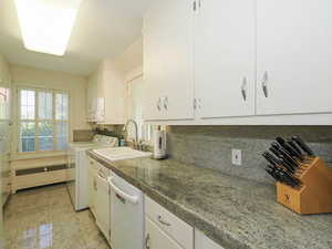 Kitchen featuring white cabinetry, white dishwasher, radiator, decorative backsplash, and dark countertops