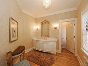 Full bath featuring crown molding, vanity, light wood-style flooring, and a chandelier