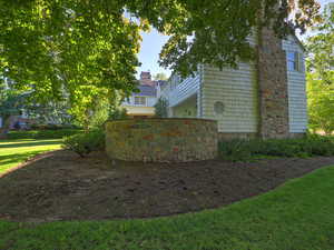 View of side of home featuring a chimney and a yard