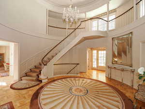 Staircase featuring a decorative wall, a towering ceiling, a chandelier, french doors, and a wainscoted wall