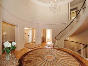 Foyer entrance featuring a high ceiling, a wainscoted wall, stairs, a decorative wall, and a chandelier