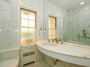 Full bathroom with tile walls and a marble finish shower
