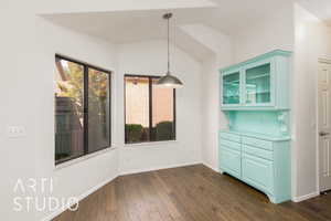 Unfurnished dining area featuring dark wood-style floors and lofted ceiling
