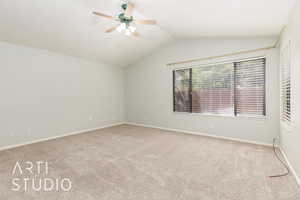 Empty room with lofted ceiling, light colored carpet, and a ceiling fan