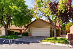 View of front facade featuring stucco siding, a tiled roof, concrete driveway, and a garage