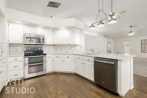 Kitchen featuring lofted ceiling, appliances with stainless steel finishes, white cabinets, and a ceiling fan