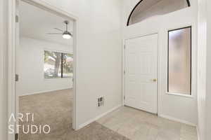 Foyer featuring ceiling fan, light colored carpet, and light tile patterned floors