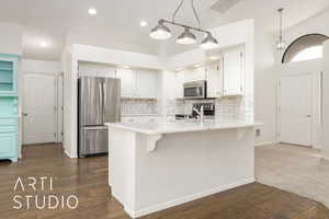 Kitchen with a kitchen bar, a peninsula, stainless steel appliances, backsplash, and recessed lighting