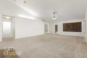 Unfurnished room with a ceiling fan, light colored carpet, and vaulted ceiling