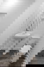 Half bath featuring baseboards and dark wood-type flooring