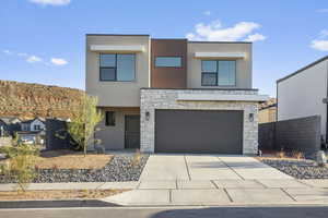Contemporary house featuring stone siding, stucco siding, an attached garage, and concrete driveway