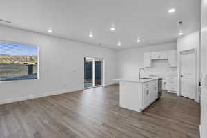 Kitchen featuring white cabinetry, recessed lighting, a center island with sink, light wood-type flooring, and light stone counters