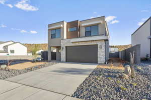 Contemporary house featuring stone siding, an attached garage, concrete driveway, and stucco siding