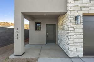 Doorway to property with stone siding, stucco siding, and a patio